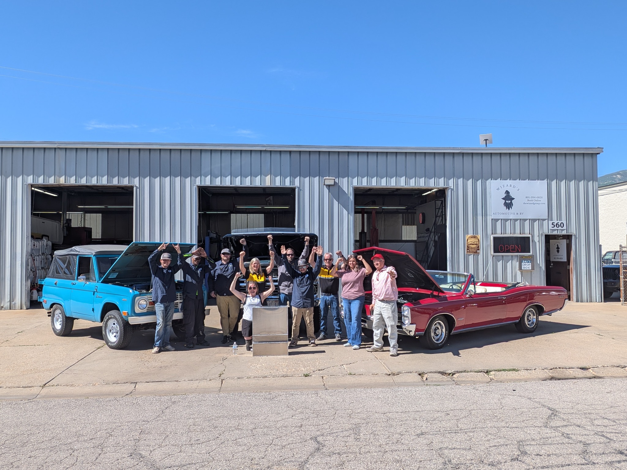 Wizard's Automotive and RV team standing together outside the Bountiful shop with classic vehicles
